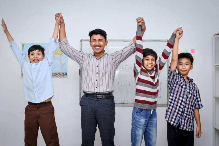 portrait-of-teacher-and-students-raising-their-han-2026-01-08-23-38-09-utc