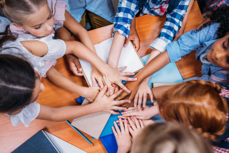 top view of team of adorable kids making team gesture